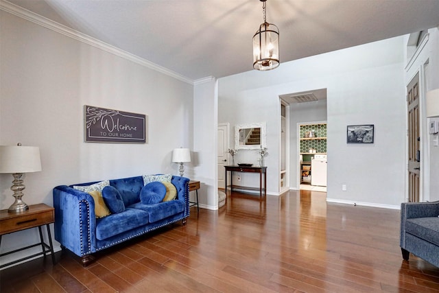 living room with dark wood-type flooring, a chandelier, and ornamental molding