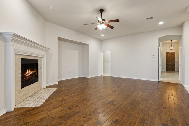 unfurnished living room featuring hardwood / wood-style flooring, ceiling fan, and a tiled fireplace