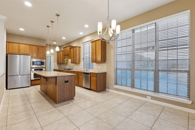 kitchen with appliances with stainless steel finishes, a kitchen breakfast bar, light stone countertops, a kitchen island, and decorative light fixtures