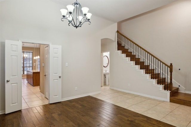 foyer entrance with a towering ceiling, ornamental molding, a chandelier, and light hardwood / wood-style floors