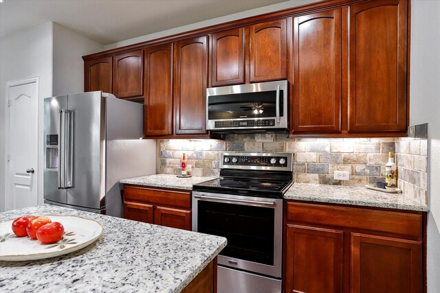 kitchen with backsplash, light stone counters, and stainless steel appliances