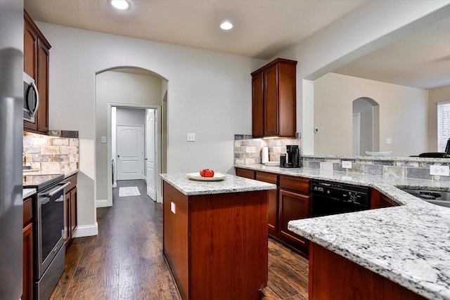 kitchen featuring light stone countertops, a center island, stainless steel appliances, dark hardwood / wood-style floors, and backsplash