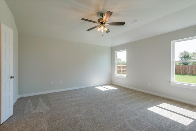 carpeted empty room featuring ceiling fan, plenty of natural light, and lofted ceiling