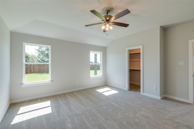 unfurnished bedroom with ceiling fan, a spacious closet, light carpet, and multiple windows