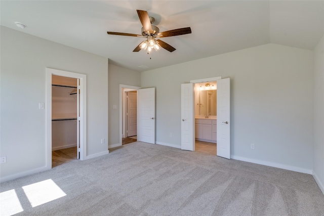 unfurnished bedroom with a walk in closet, light colored carpet, ceiling fan, connected bathroom, and a closet