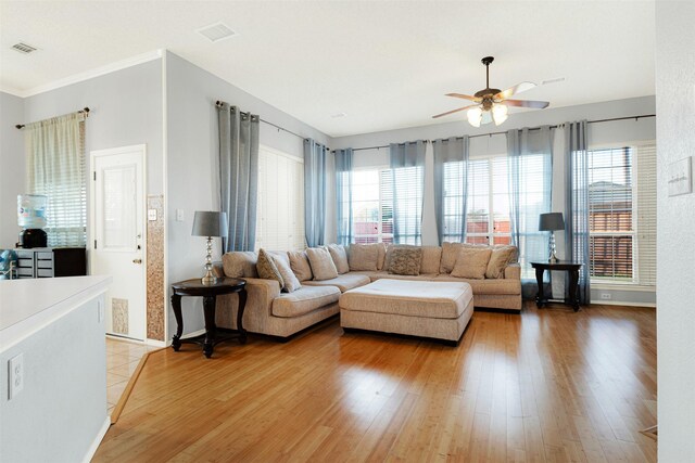 living room featuring hardwood / wood-style flooring, ceiling fan, and crown molding