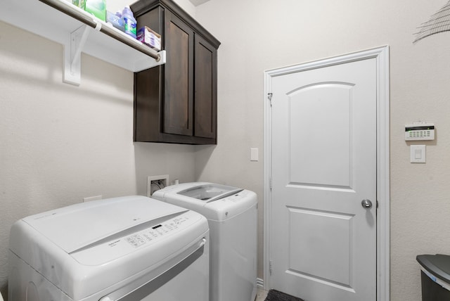 clothes washing area with washing machine and dryer and cabinets