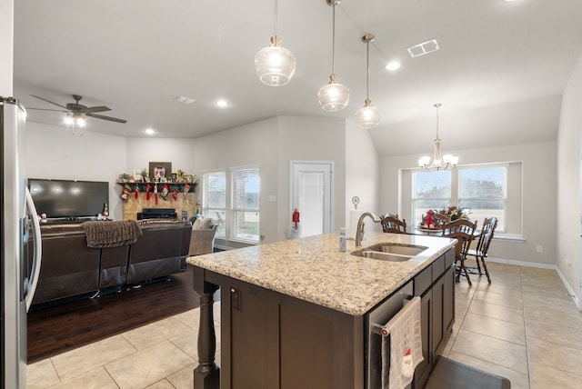 kitchen featuring ceiling fan with notable chandelier, sink, pendant lighting, a stone fireplace, and light tile patterned flooring