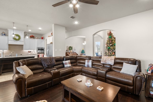 living room featuring ceiling fan, sink, and dark hardwood / wood-style floors