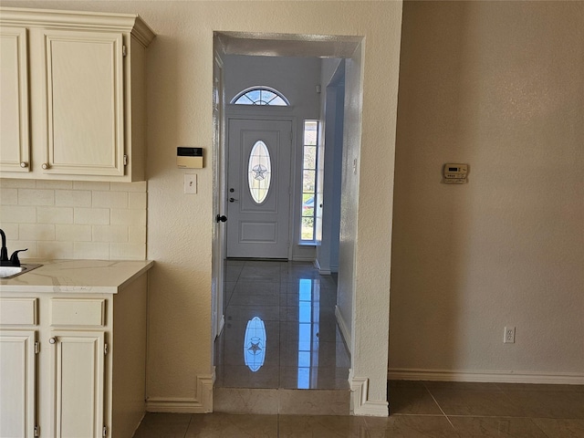 entryway featuring a wealth of natural light, sink, and dark tile patterned flooring