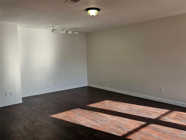 unfurnished room featuring dark hardwood / wood-style floors and track lighting