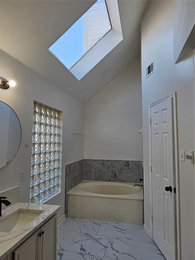 bathroom featuring a tub, vaulted ceiling with skylight, and vanity