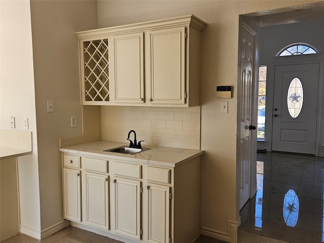 interior space featuring backsplash, sink, tile patterned floors, and cream cabinets