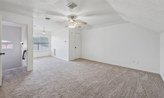 additional living space with a textured ceiling, light colored carpet, vaulted ceiling, and ceiling fan