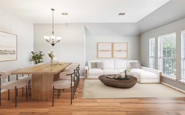 living room with light hardwood / wood-style floors, a wealth of natural light, and an inviting chandelier