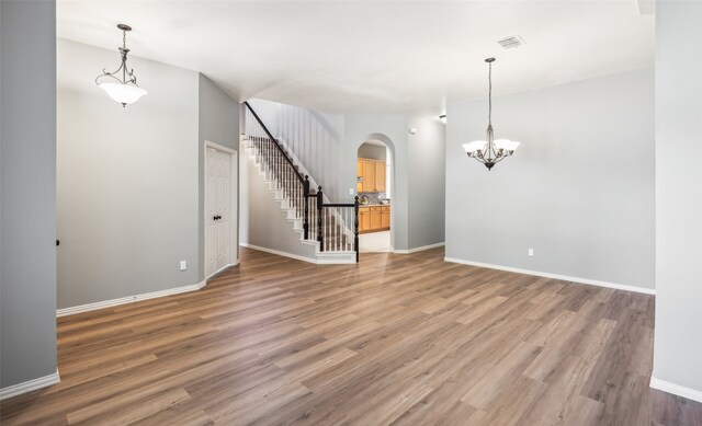 unfurnished living room featuring a notable chandelier and hardwood / wood-style flooring