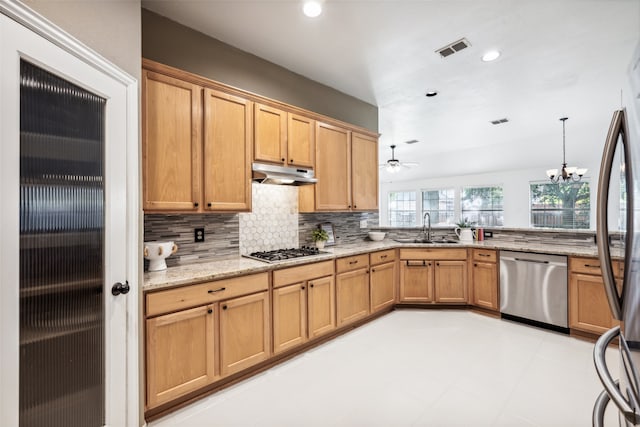 kitchen with backsplash, ceiling fan with notable chandelier, sink, light stone countertops, and appliances with stainless steel finishes