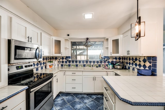 kitchen with sink, stainless steel appliances, tasteful backsplash, decorative light fixtures, and white cabinets