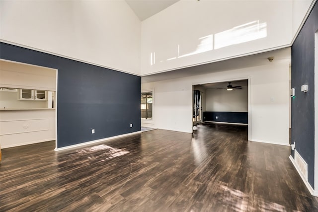 unfurnished living room with dark hardwood / wood-style floors, ceiling fan, and high vaulted ceiling