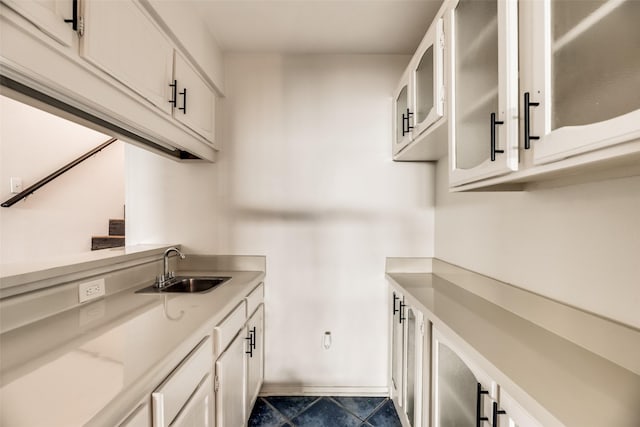 kitchen with white cabinets, light stone counters, and sink