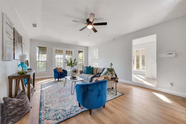 living room featuring ceiling fan, french doors, and light wood-type flooring