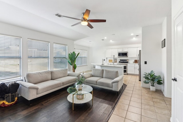 living room featuring ceiling fan, light wood-type flooring, and sink