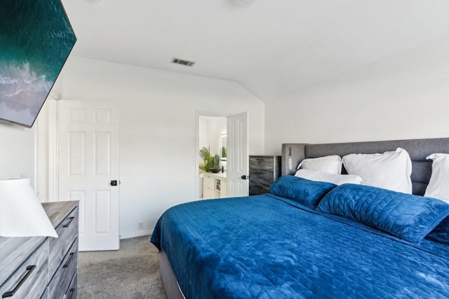 carpeted bedroom featuring lofted ceiling and ensuite bath