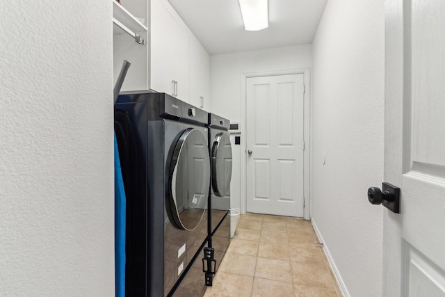 clothes washing area featuring cabinets, light tile patterned floors, and washer and dryer