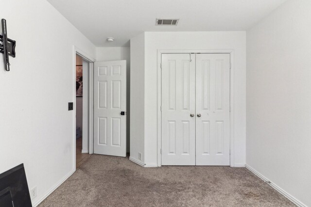 unfurnished bedroom featuring a closet and light colored carpet