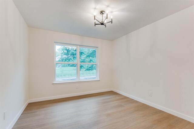 empty room with a notable chandelier and light hardwood / wood-style flooring