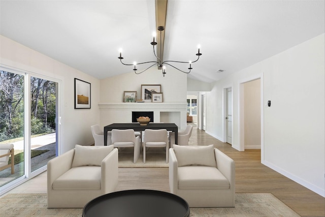 living room with an inviting chandelier, vaulted ceiling, and light wood-type flooring