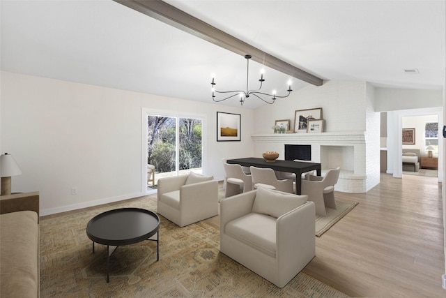 living room with light hardwood / wood-style floors, lofted ceiling with beams, a notable chandelier, and a fireplace