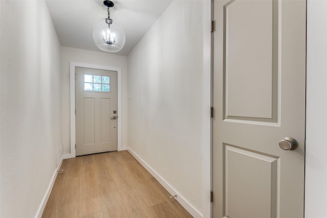 doorway with light hardwood / wood-style flooring and a notable chandelier