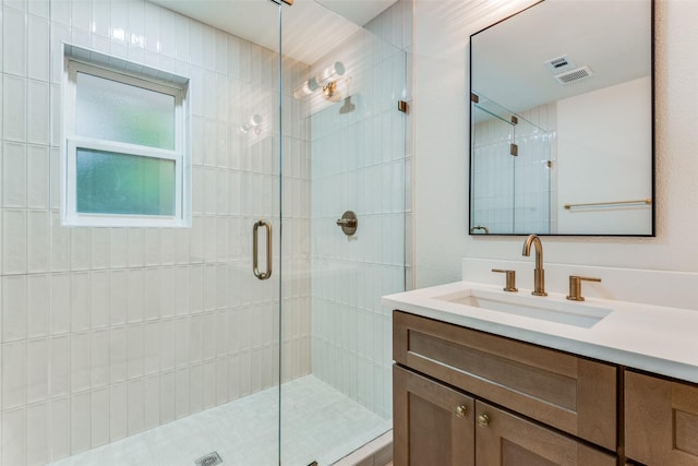 bathroom featuring a shower with door and vanity