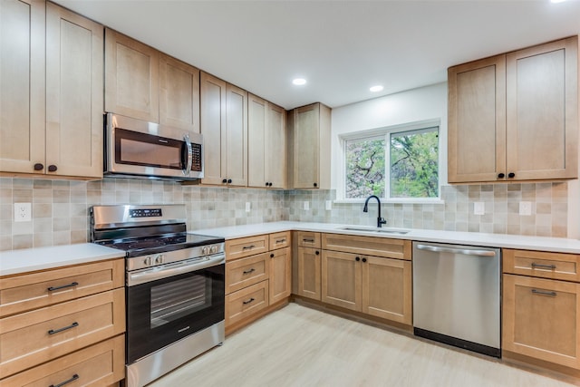 kitchen with appliances with stainless steel finishes, tasteful backsplash, light hardwood / wood-style flooring, and sink