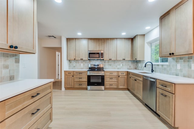 kitchen with light brown cabinets, stainless steel appliances, light hardwood / wood-style floors, and sink