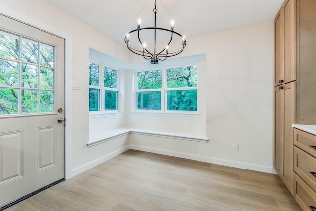 unfurnished dining area with a chandelier and light hardwood / wood-style floors