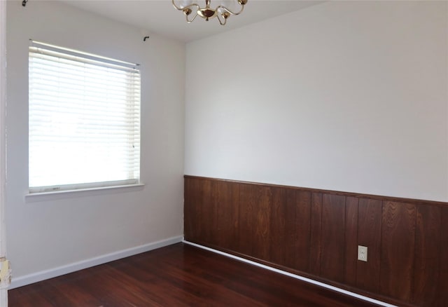 spare room with dark hardwood / wood-style flooring, plenty of natural light, and an inviting chandelier