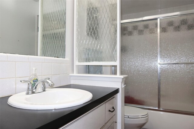 full bathroom with shower / bath combination with glass door, vanity, backsplash, and toilet