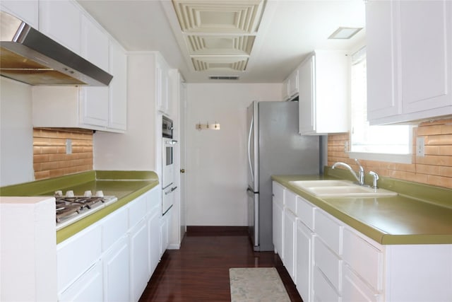 kitchen featuring sink, white cabinets, and range hood