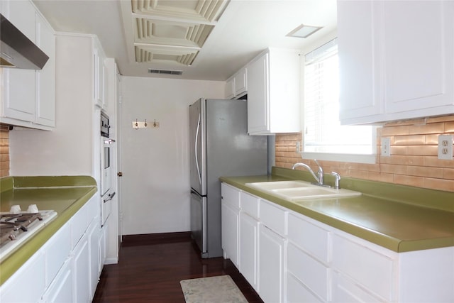 kitchen featuring decorative backsplash, white appliances, wall chimney range hood, sink, and white cabinetry