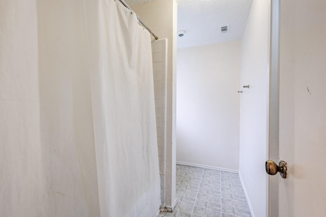 bathroom with a shower with shower curtain and a textured ceiling