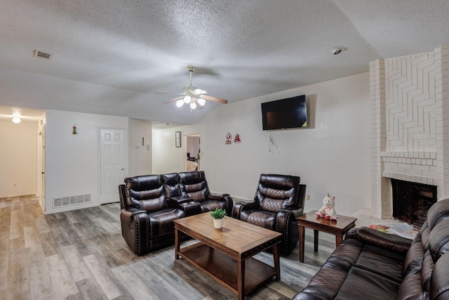 living room featuring a fireplace, hardwood / wood-style flooring, vaulted ceiling, and ceiling fan