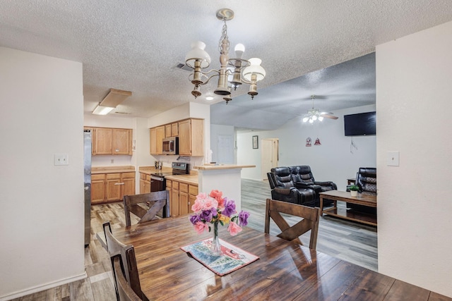 dining space with hardwood / wood-style flooring, ceiling fan with notable chandelier, and a textured ceiling