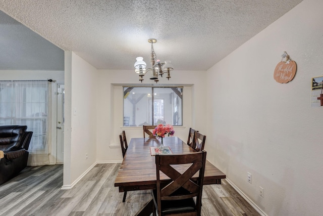 dining room featuring a chandelier, wood-type flooring, and a textured ceiling