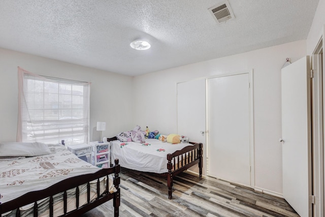 bedroom with wood-type flooring and a textured ceiling