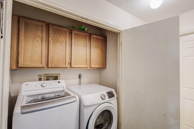 clothes washing area with cabinets, a textured ceiling, and washing machine and clothes dryer