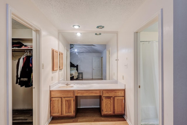 bathroom featuring curtained shower, vanity, a textured ceiling, and hardwood / wood-style flooring