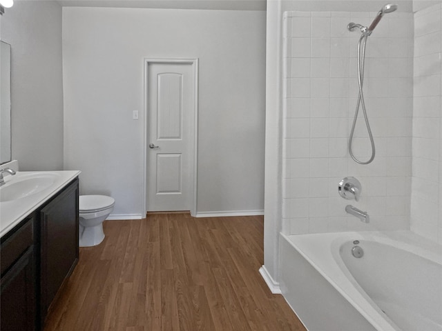 full bathroom featuring hardwood / wood-style floors, vanity, toilet, and tiled shower / bath combo