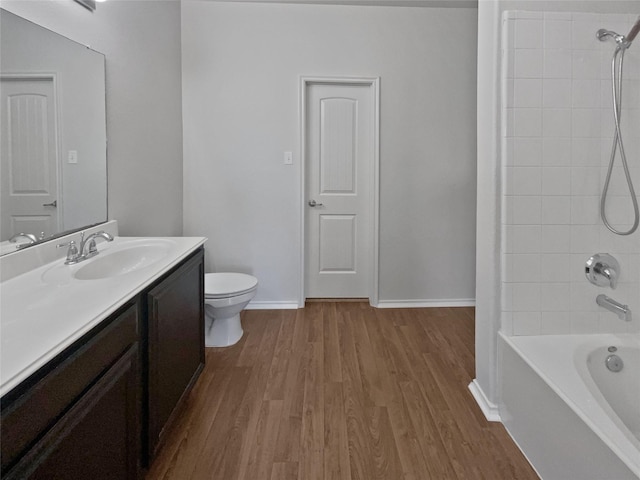 full bathroom with hardwood / wood-style flooring, vanity, toilet, and tiled shower / bath